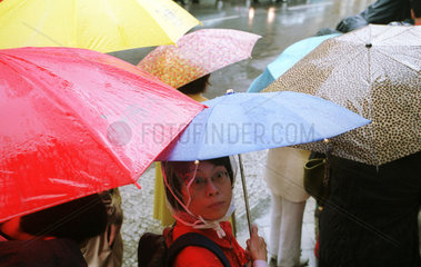 Asiatische Touristen unter Regenschirmen in Berlin