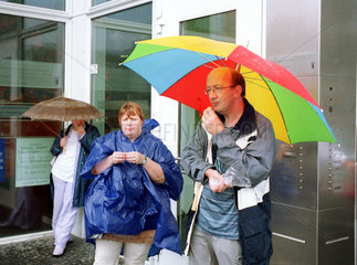 Menschen stehen im Regen mit Schirmen und essen
