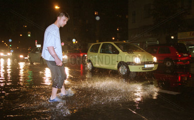 Mann und PKW in einer ueberfluteten Strasse in Berlin