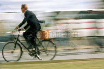 Mann im Anzug auf dem Fahrrad im Stadtverkehr