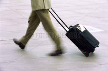 Laufende Beine eines Mannes mit Koffer und Zeitung