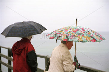 Zingst  Rentnerpaar unter Regenschirmen