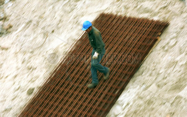 Bauarbeiter laeuft auf einem Stahlgitter hinunter