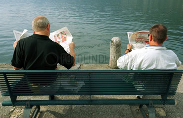 Maenner lesen Zeitung am Lago Maggiore/ Schweiz