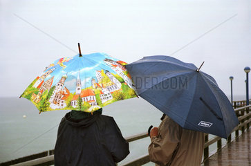Zingst  Menschen unter Regenschirmen am Meer