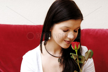 Berlin  eine junge Frau riecht an einer Rose