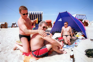 Spielende u. sich sonnende Herren am Strand der Ostsee