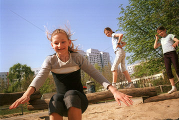 Maedchen toben auf einem Spielplatz in Berlin