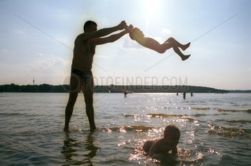 Silhouette eines Vaters mit seinen Kindern im Wasser