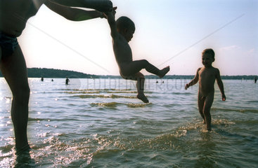 Silhouette eines Vaters mit seinen Kindern im Wasser