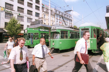 Maenner mit Krawatten vor Strassenbahnen in Basel