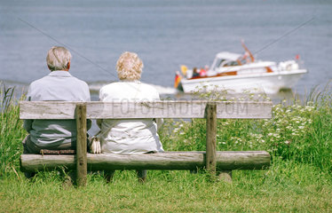 Rentnerpaar schaut einem Boot nach