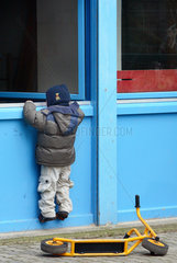 Berlin  Junge schaut in ein geoeffnetes Fenster