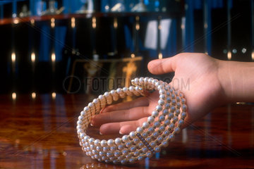 Hand haelt teure Perlen-Halskette