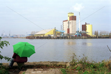 Angler mit Regenschirm und Maelzerei im Bremer Hafen