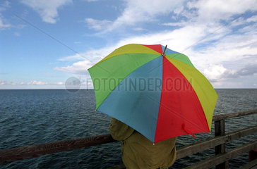 Zingst  Mann unter buntem Regenschirm am Meer