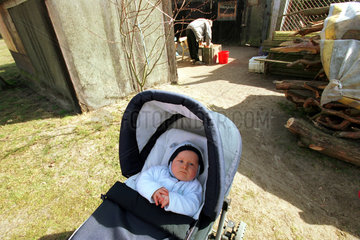 Baby im Kinderwagen auf einem Hof in Brandenburg