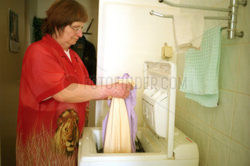 Frau fuellt Waschmaschine  Berlin