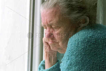 Alte Frau schaut aus Fenster  Brandenburg