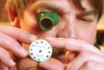 Uhrmacher mit Lupe prueft Uhrwerk  Berlin