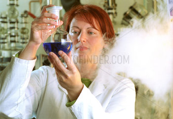 Chemielaborantin mit Glaskolben und Dampf