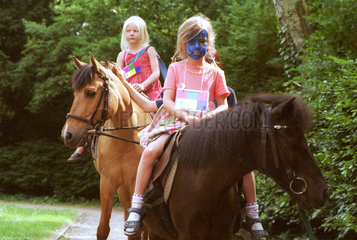 Zwei kleine Maedchen reiten auf Ponys