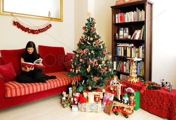 Berlin  eine Frau liest vor dem Weihnachtsbaum