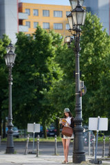 Berlin  Deutschland  Touristin lehnt an einer alten Gaslaterne und studiert den Stadtplan