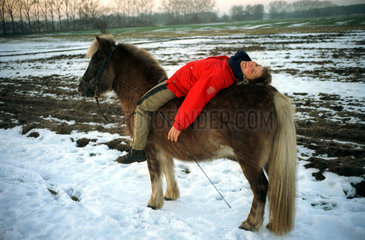 Cottbus  Frau liegt auf Island-Pony
