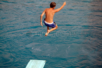 Berlin  Junge springt vom Sprungbrett ins Wasser