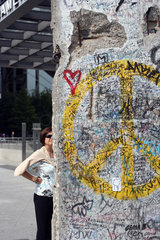 Berlin  Touristin betrachtet das Mauersegment