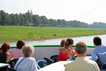 Koeln  Fahrgaeste einer Rheinfahrt schauen auf die Rheinwiesen