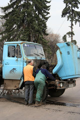 Moskau  Zwei Maenner reparieren einen LKW