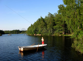 Karlskrona  Schweden  ein Kind steht im Ruderboot und angelt