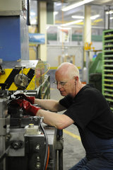 Schwyz  Schweiz  ein Mann bei einer Maschine zur Herstellung von Victorinox Taschenmessern