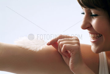 Berlin  junge Frau streichelt ihren Arm mit einer Feder
