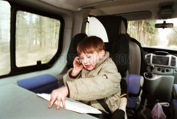 Junge mit Handy auf Kindersitz im Auto  Norddeutschland