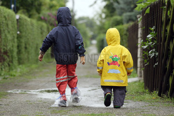 Berlin  Kinder in Regenkleidung laufen einen Weg entlang
