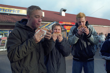 Jugendliche essen Doener vor einem Supermarkt