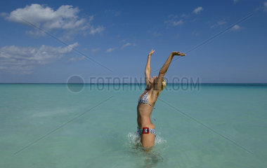 Junge Frau steht mit geoeffneten Armen im Wasser  Bahamas