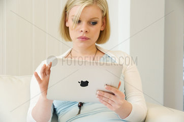 Hamburg  Deutschland  eine junge Frau auf dem Sofa mit dem IPad von Apple