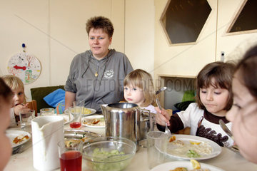 Berlin  Kinder sitzen gemeinsam mit einer Erzieherin am Tisch und essen zu Mittag