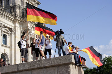 Berlin  Fussballfans mit deutscher Fahne vor Reichstag
