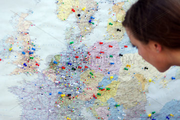 Berlin  Frau guckt auf eine Europakarte  in die Stecknadel gesteckt sind