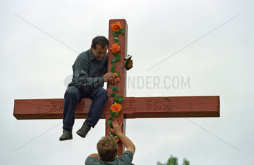 Maenner beim Schmuecken eines Kreuzes  Polen