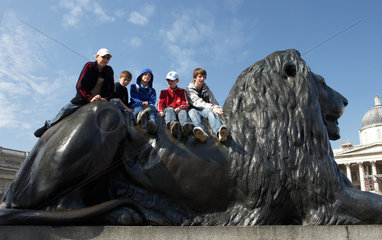 London - Jungs auf einem Bronzeloewen am Trafalgar Square