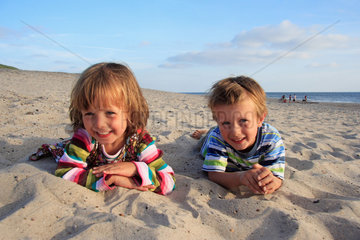 Daenemark  Maedchen und Junge liegen im Sand