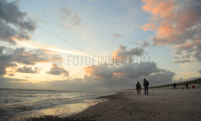 Daenemark  Urlauber am Strand bei Sonnenuntergang