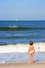 Hvide Sande  Maedchen steht am Strand und schaut auf die Nordsee