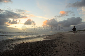 Daenemark  Jogger am Strand bei Sonnenuntergang